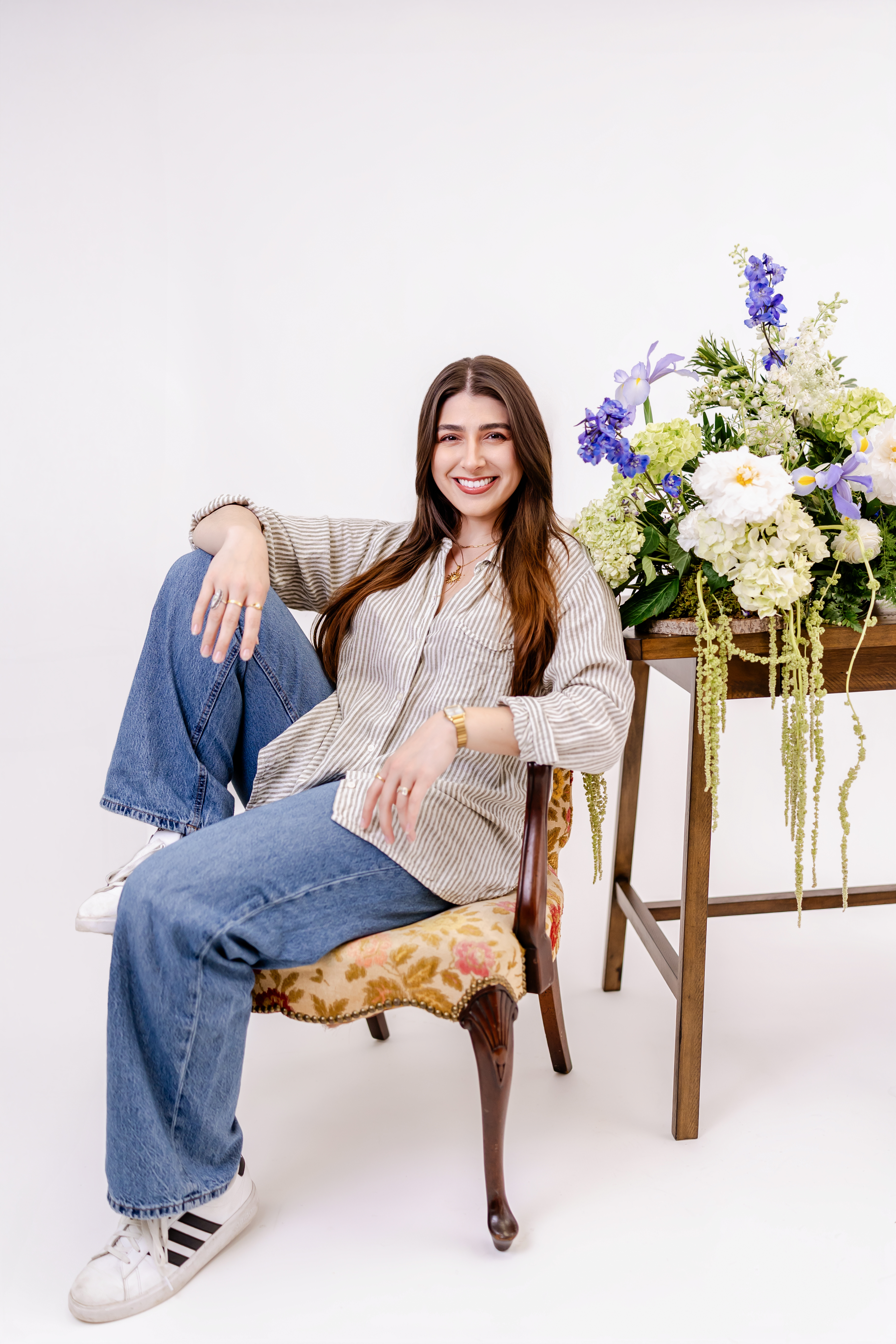 Maryland wedding florist smiling beside a garden-style floral arrangement with white and blue flowers