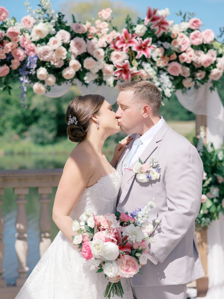 Bride and groom posing with pink, blue, and white bouquet at spring wedding
